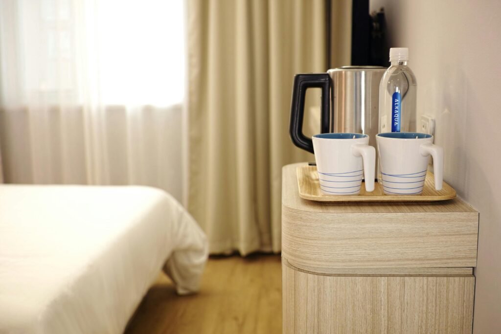 Contemporary hotel room featuring a neatly arranged beverage setup on wooden furniture.