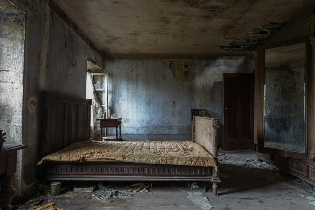 Explore the haunting beauty of an abandoned rustic bedroom, displaying decayed furniture and peeling walls.